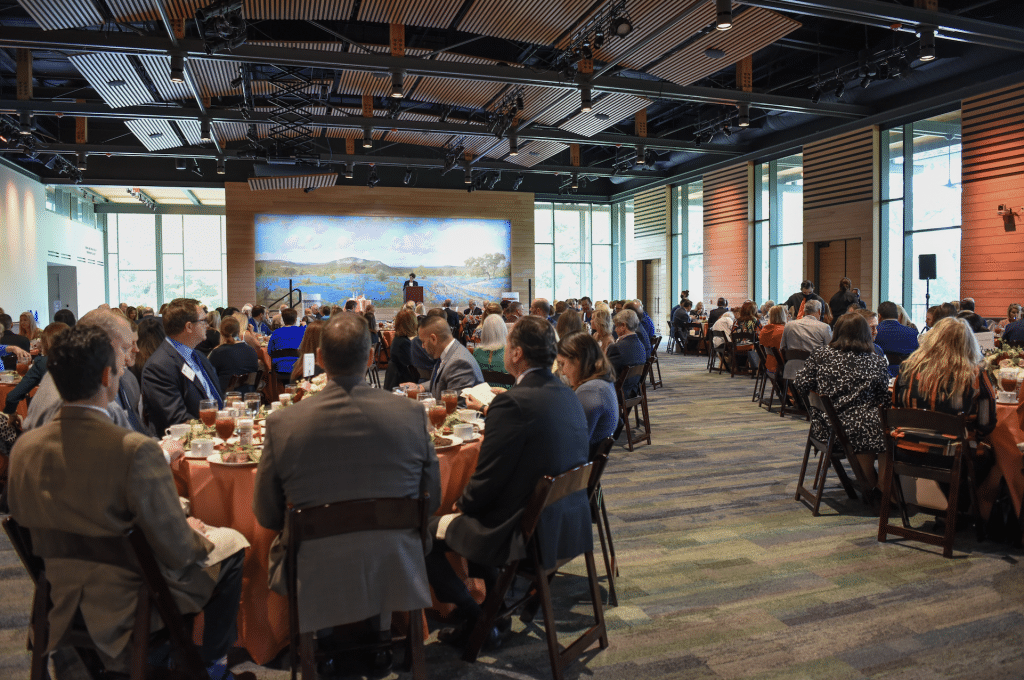 Attendees sitting at tables, listening to speakers.