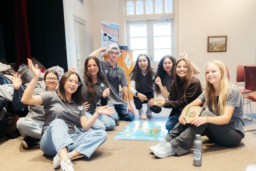 teenagers sitting on the floor, smiling.