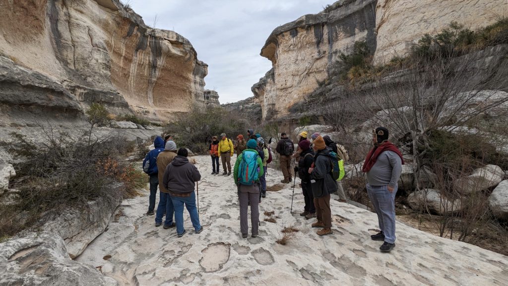 group of hikers stand in canyon.