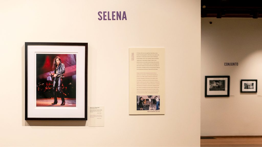 A gallery with cream walls and wooden floor, with framed photos on display